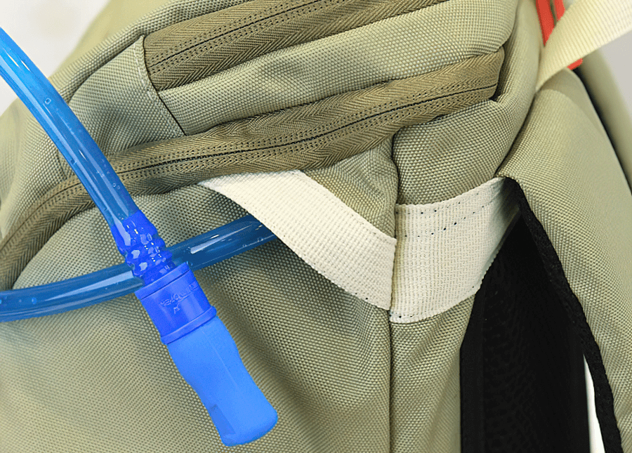 Close-up of khaki travel backpack with hydration tube, showcasing durable fabric and reinforced stitching.